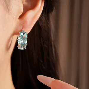 Primo piano di eleganti orecchini a cerchio in argento con zirconi blu cielo taglio squadrato