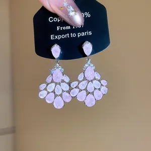 Vue rapprochée de boucles d'oreilles pompons roses scintillantes avec des accents de zircon