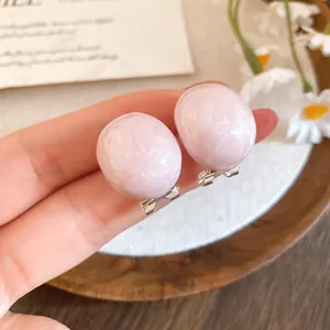 Close-up of pink oval drop-oil earrings showing the texture and clip-on design details.