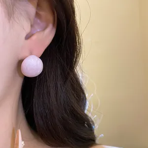 Close-up detail of elegant pink oil-drop stud earring with minimalist round design