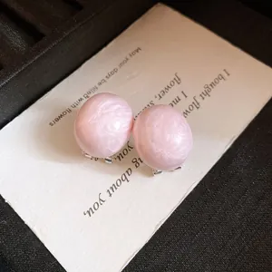 Detail showing pink oval earrings with marbled texture on a vintage white text card
