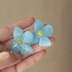 Detailed view of handmade blue acrylic flower earrings with retro French design aesthetic