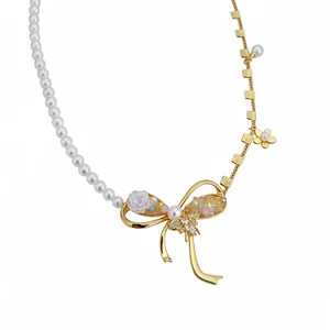 Elegant asymmetrical pearl necklace with a gold bow pendant and zircon bee accents