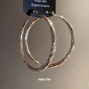 Boucles d'oreilles créoles argentées texturées avec un design géométrique élégant