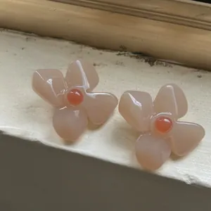 Macro shot of French vintage acrylic flower earrings with orange center stone details.