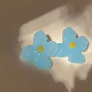 Macro detail shot of blue acrylic flower earrings with a jelly-like translucent texture