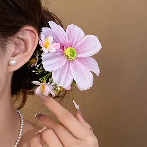 Gros plan d'une pince à cheveux romantique en fleur de tissu rose portée par un mannequin.