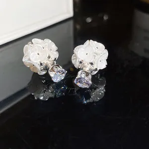 Close-up of elegant white flower double-sided stud earrings with sparkling crystals.