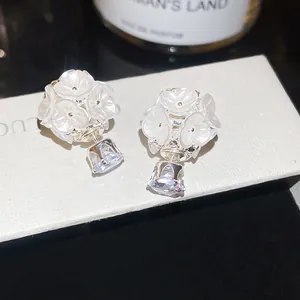 Close-up of sweet white flower earrings with crystal drop pendants in front-back style.