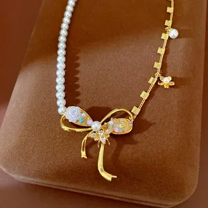 Exquisite detail of a pearl necklace featuring a zircon bee and golden bow pendant