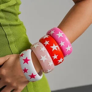 Detail view of colorful resin bangles with contrasting star patterns on model arm