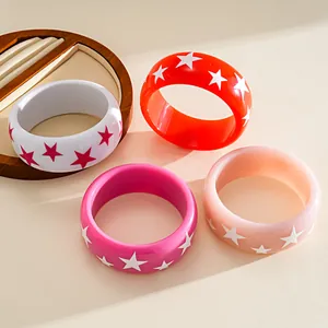 Macro view of four vibrant resin bangles with colorful star patterns and glossy finish