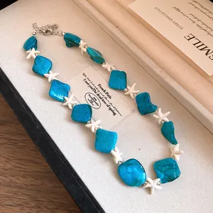 Primo piano di perline blu e stelle marine bianche su collana per vacanze estive