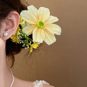 Détail d'une grande pince à cheveux fleur en tissu jaune pour un style de forêt doux et élégant.
