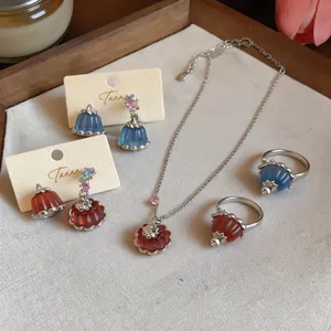 Macro view of dainty resin pudding pendants and zircon earrings in an elegant jewelry collection.