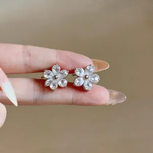 Close-up detail of silver-toned flower stud earrings with clear zircon petals.