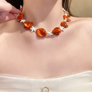 Dettaglio ravvicinato di una collana di perle di conchiglia arancione e stella marina