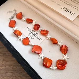 Primo piano di una collana con perline arancioni e stelle marine bianche in stile resort