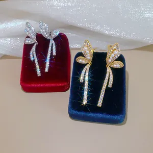 Detail view of butterfly ear clips with pearls and cubic zirconia on velvet boxes.