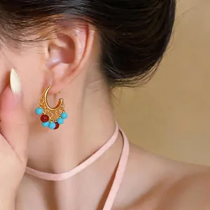 Macro detail shot of 18k gold plated C-shaped hoop earrings with colorful resin beads.