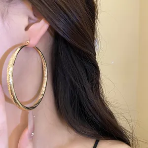Gros plan de grandes créoles dorées facettées sur un mannequin vu de profil