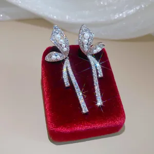 Detail view of sparkling butterfly earrings with pearls and zircons on red velvet