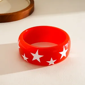 Close-up of a red resin bangle featuring white star patterns in a dopamine style.