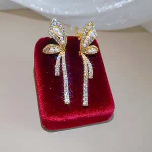 Close-up of luxury 18k gold plated butterfly clip-on earrings with zircons and pearls.