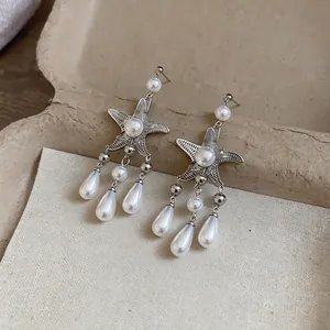 Vue détaillée des boucles d'oreilles étoile de mer avec élégants pompons de perles gouttes