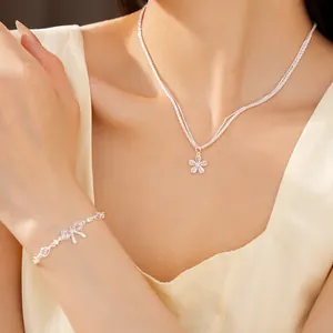Dettaglio di un set gioielli argento con collana a fiori e bracciale con fiocco e zirconi