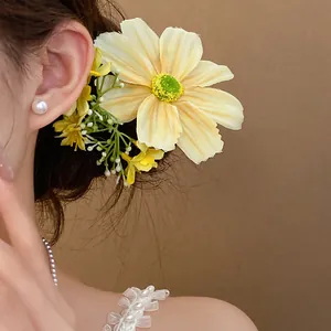 Détail d'une pince à cheveux en fleur de tissu jaune portée par un modèle style forestier