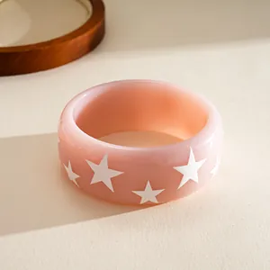 Detailed macro shot of a chunky pink resin bangle with white star pattern decorations