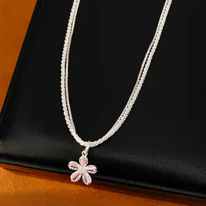 Dettaglio di una collana a doppia catena in argento con ciondolo a fiore in zircone rosa