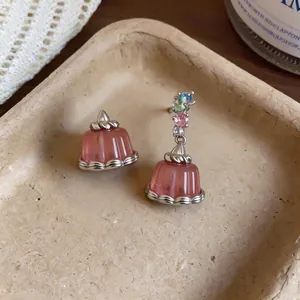 Asymmetric pink resin pudding earrings featuring colorful zircon stones in lifestyle setting