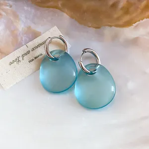Dettaglio di orecchini a goccia in acrilico blu traslucido con cerchi argento