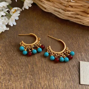 Detailed macro view of 18k gold plated C-shaped earrings with ethnic colorful beads