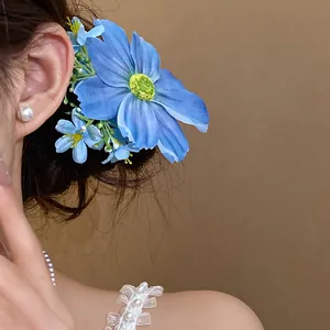 Détail d'une pince à cheveux en fleur de tissu bleu portée par un mannequin de style forêt.