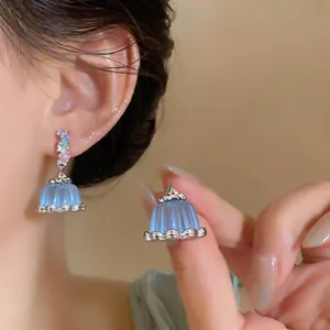 Close-up of elegant blue resin pudding drop earrings with colorful zircon studs detail