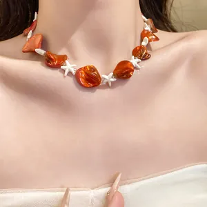 Primo piano di una collana di perline con stelle marine bianche e conchiglie arancioni