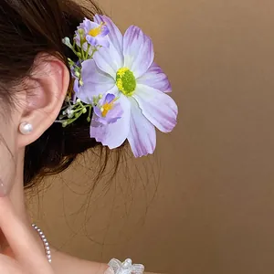 Vue rapprochée d'une pince à cheveux fleur en tissu violette portée par un mannequin