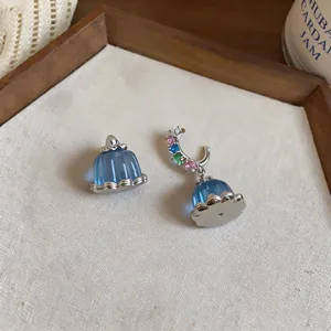 Macro view of dainty blue resin pudding earrings with colorful zircon stone accents.