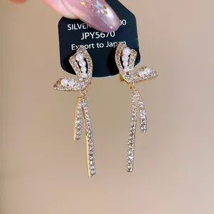 Close-up of 18k gold plated butterfly clip earrings with sparkling zircons and pearls.