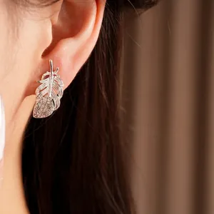 Elegantes pendientes de botón de pluma de plata con diamantes brillantes en la oreja