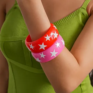 Close-up view of vibrant red and pink resin bangles with white star patterns.