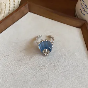 Macro view of an elegant silver-toned ring featuring a blue resin pleated charm and tiny zircons.