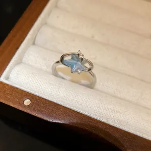Dettaglio ravvicinato di un anello argento con motivo a stella marina blu e zircone