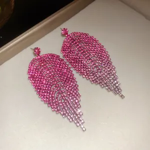 Close-up detail van elegante bladvormige kwastjesoorbellen met roze strassteentjes