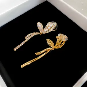 Detailed view of gold butterfly ear clips with pearls and zircon in a black jewelry box
