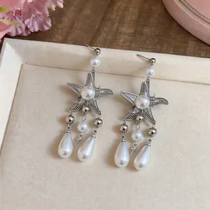 Gros plan détaillé de boucles d'oreilles étoile de mer avec perles en forme de goutte