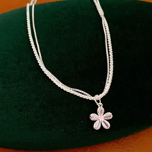 Primo piano di una collana d'argento a doppio strato con pendente a fiore in zircone rosa.